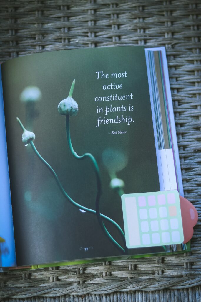 book open to a page with garlic scapes growing and a quote about herbalism